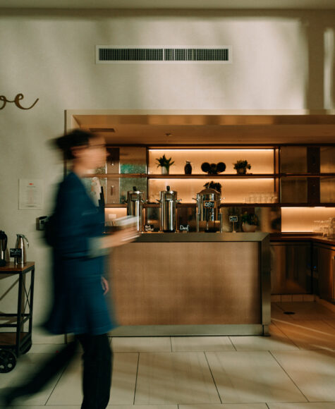 Hotel coffee bar with blurred person walking past.