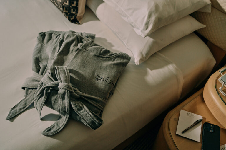 Folded gray robe on hotel bed.