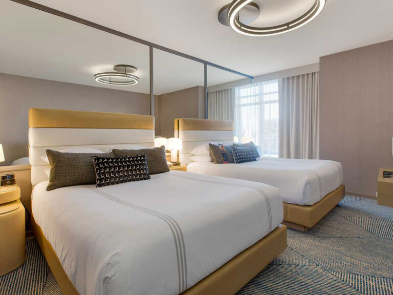 Two queen beds in bright hotel room.