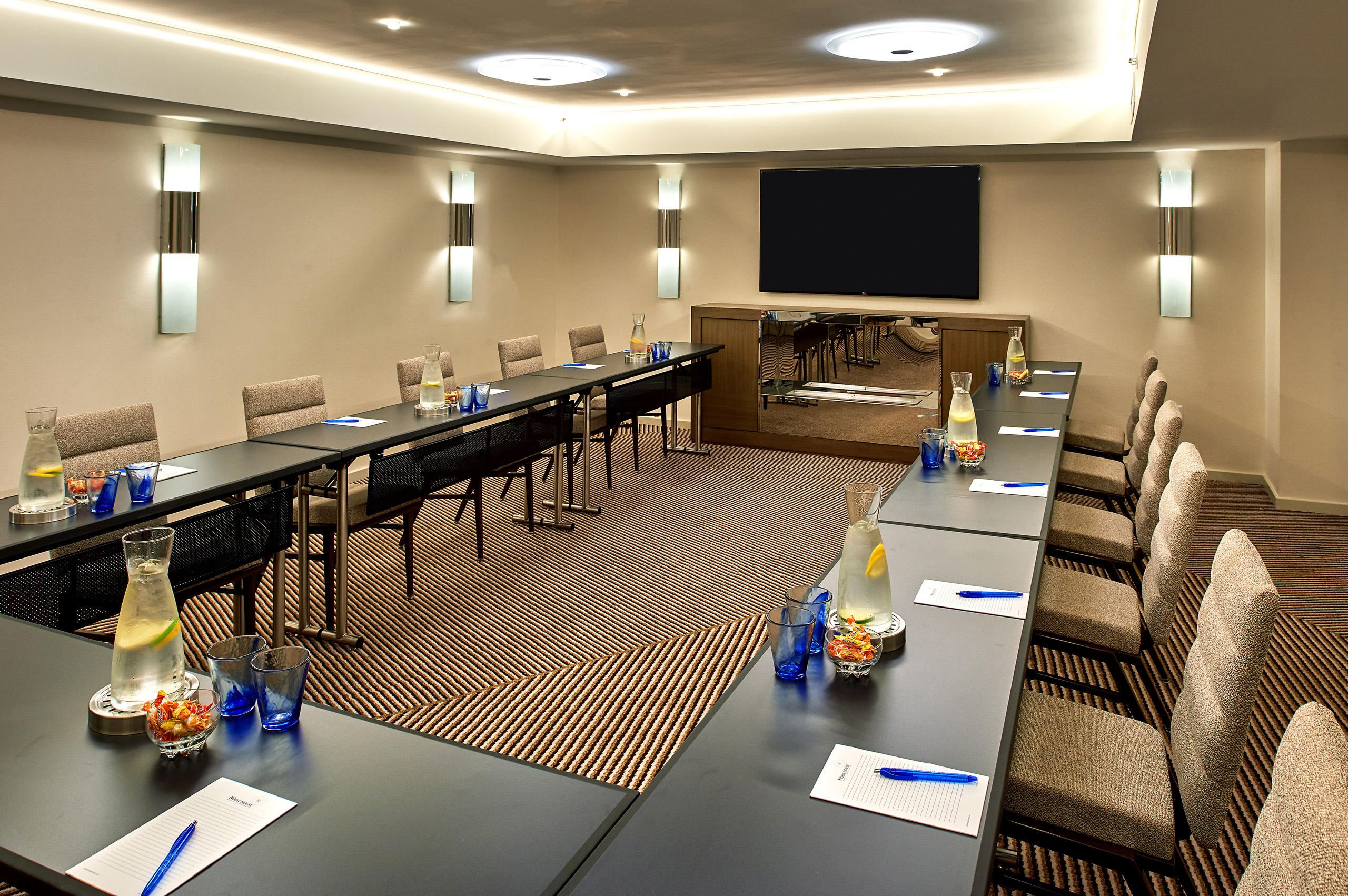 Conference room with U-shaped tables and presentation screen