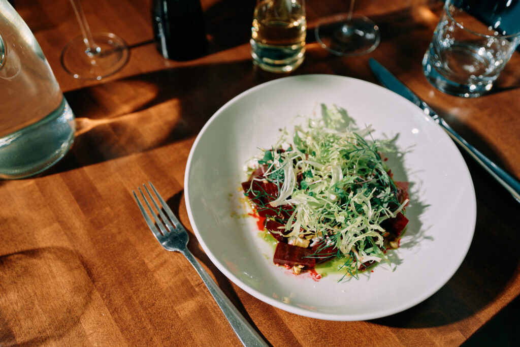 Beet salad topped with frisée greens in natural light.