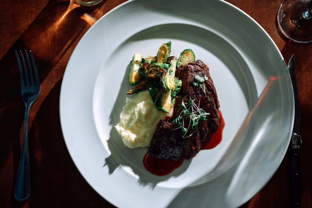 Steak with mashed potatoes and Brussels sprouts on white plate.