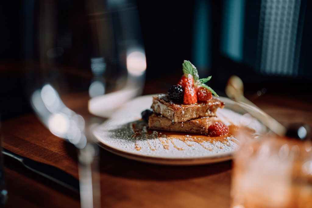 French toast with berries and mint on a restaurant table.