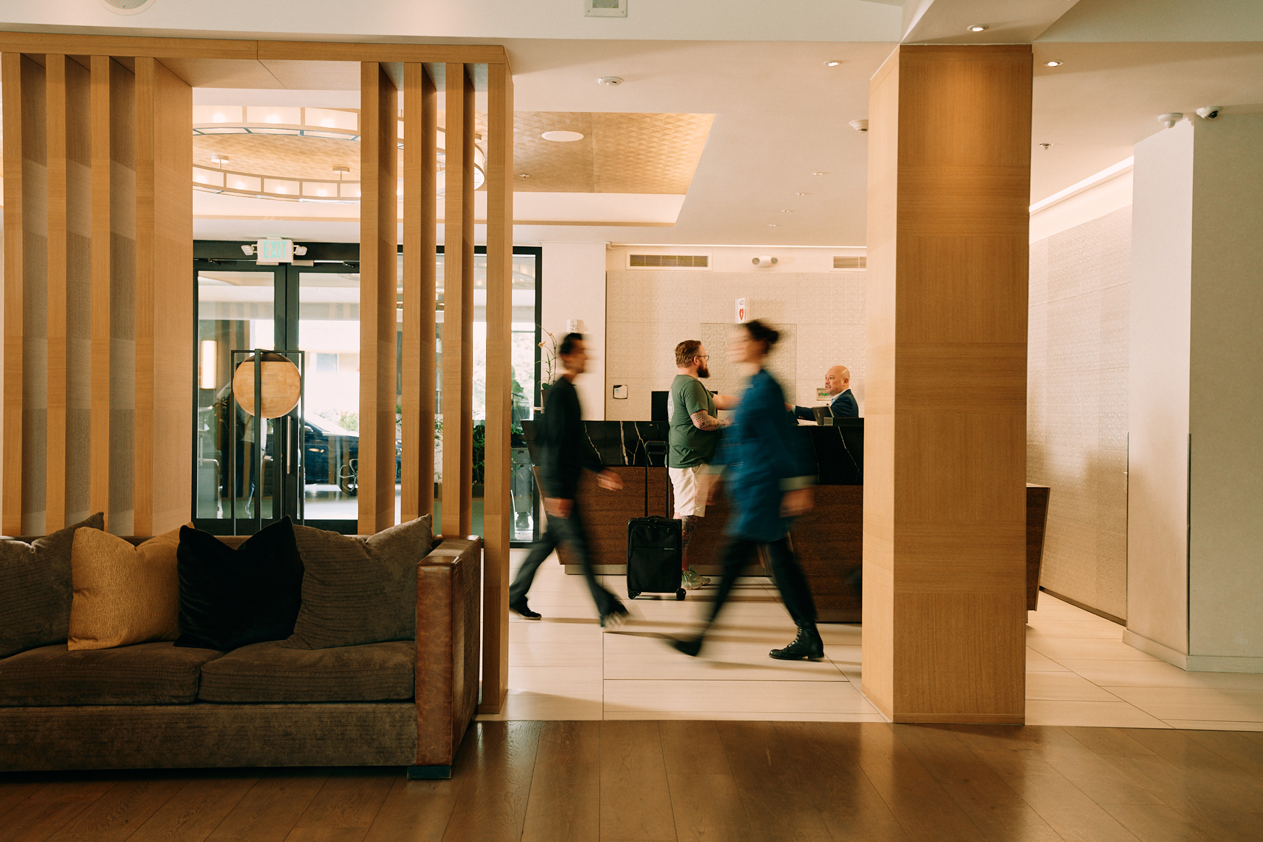 Hotel lobby with guests walking past check-in desk.