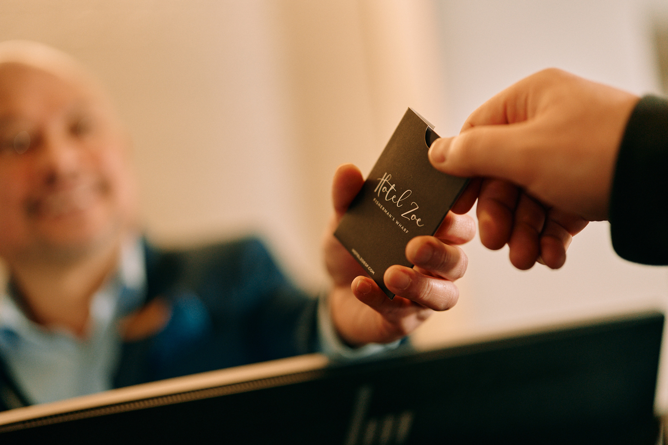 Guest receives Hotel Zoe room key from front desk staff.
