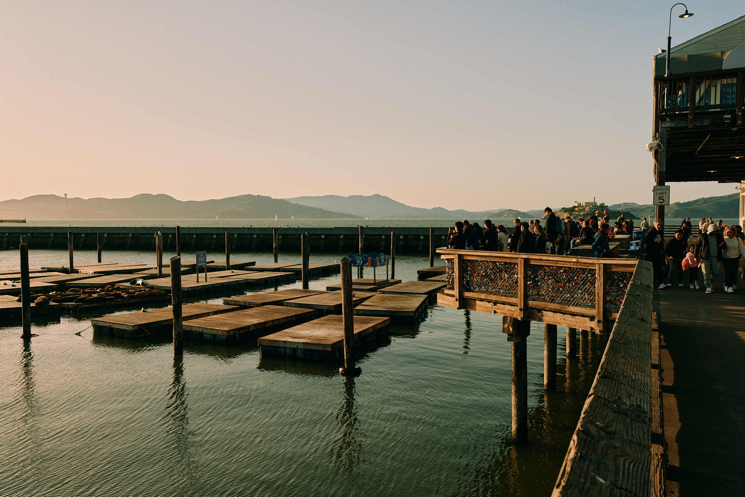 people on dock viewing sunset with mountains in the background
