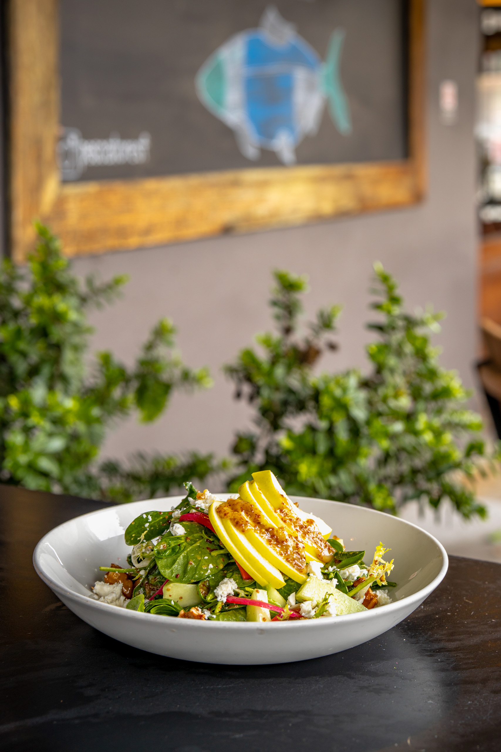 Fresh salad topped with sliced yellow squash.