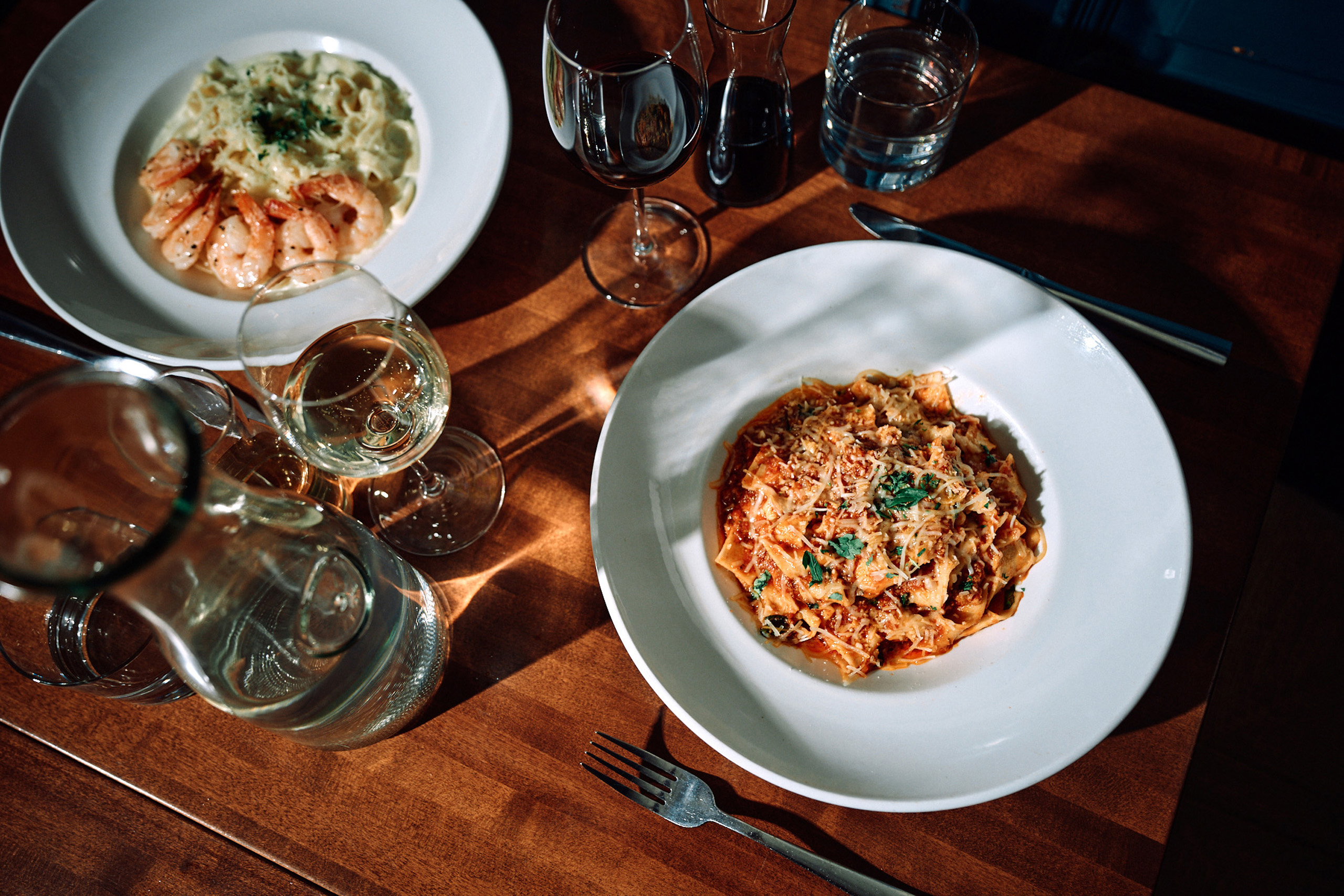 Plates of pasta and wine on a restaurant table.