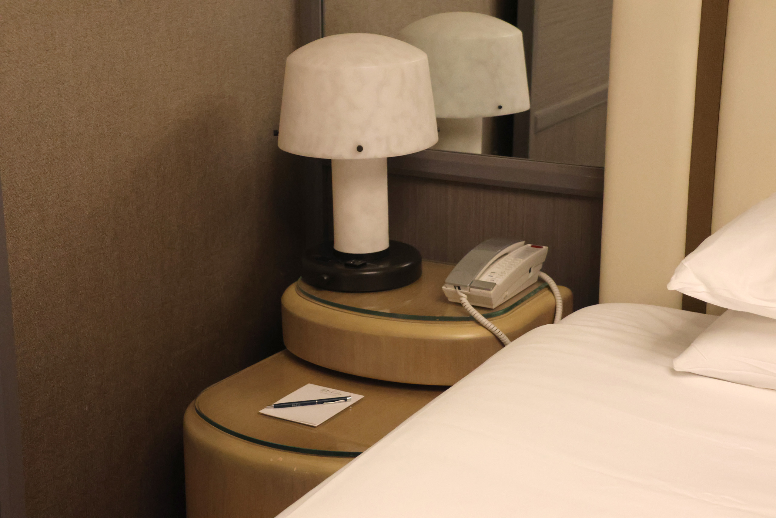 Bedside table with lamp, phone, and notepad.
