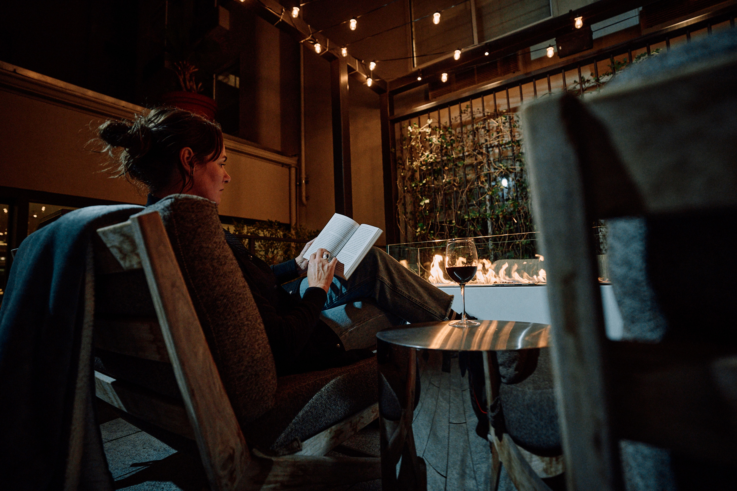Person reading by outdoor firepit at night