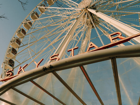 Skystar Ferris wheel towering upward against clear blue sky.
