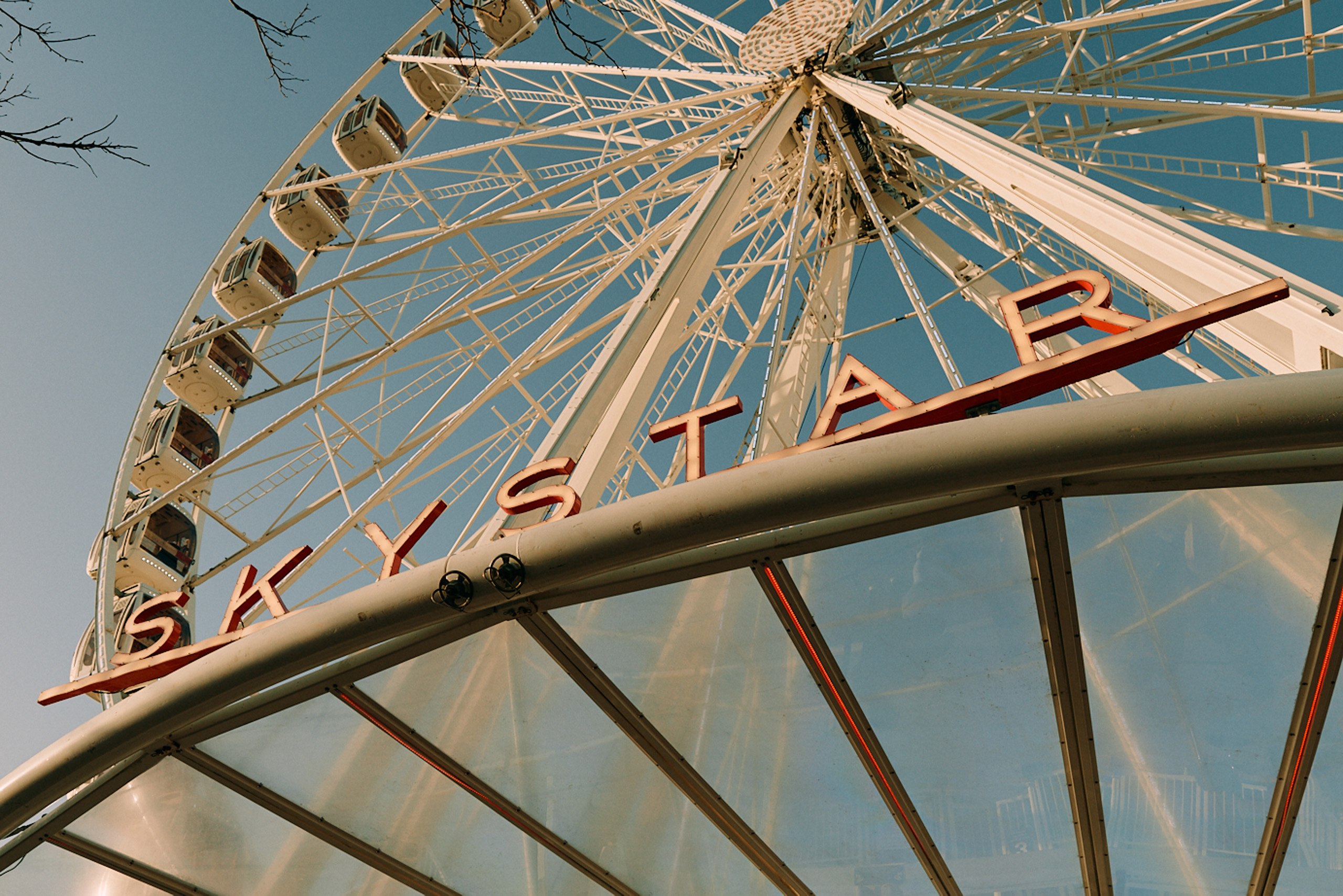 Skystar Ferris wheel towering upward against clear blue sky.
