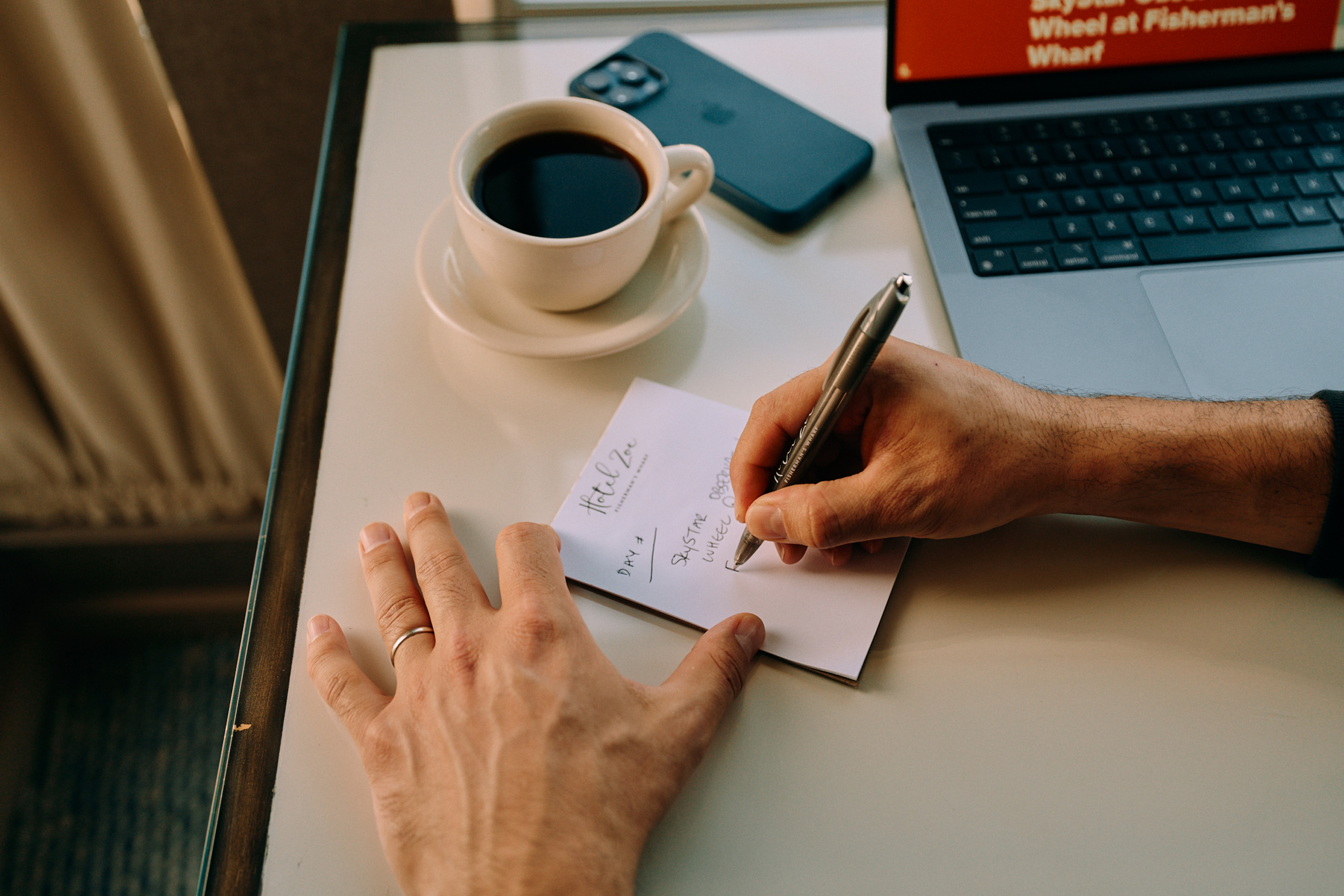 Handwriting notes beside coffee and laptop.