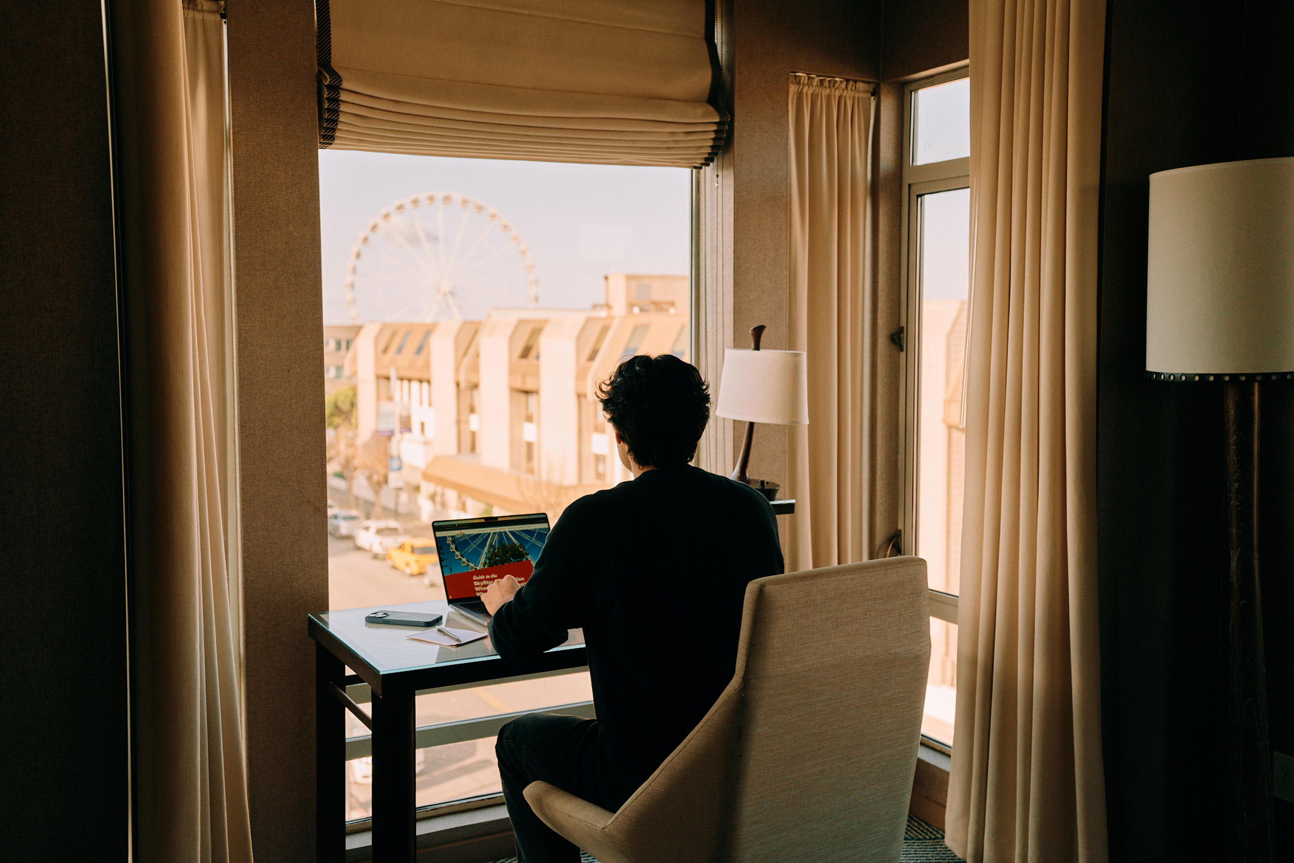 Guest working at desk with Ferris wheel view.