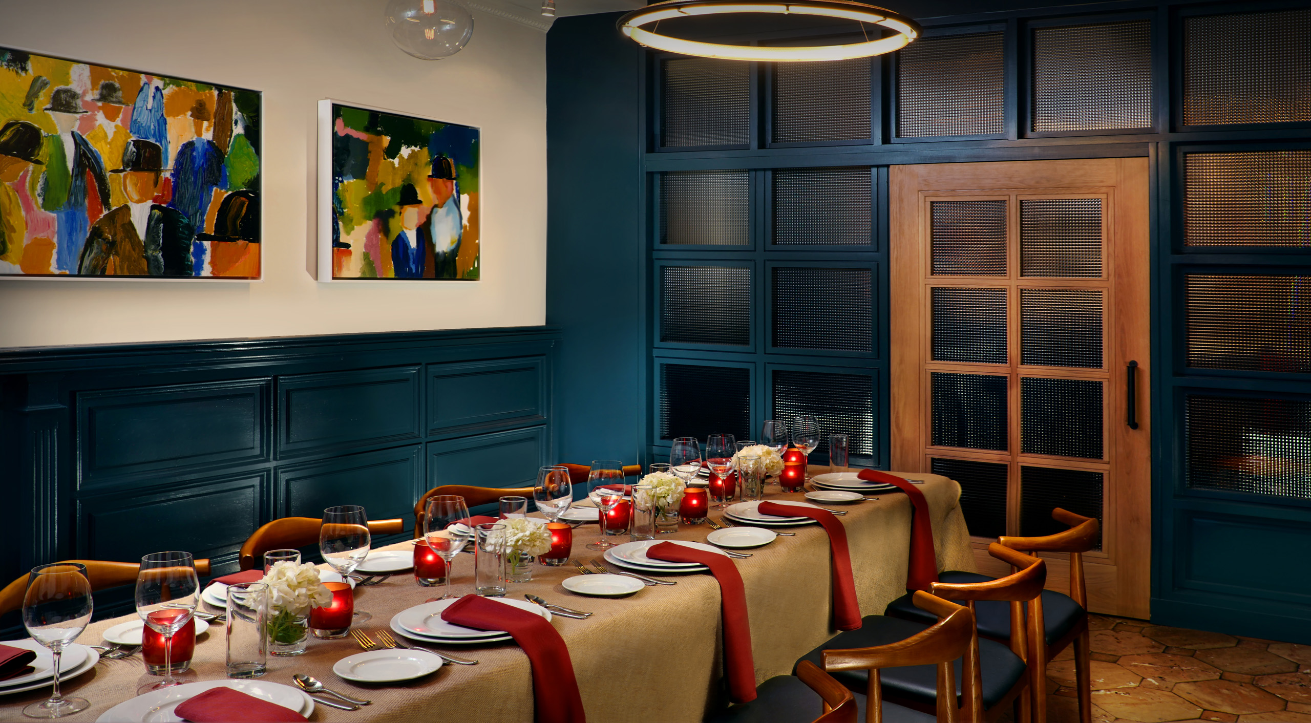 Private dining table set with red napkins and candles.