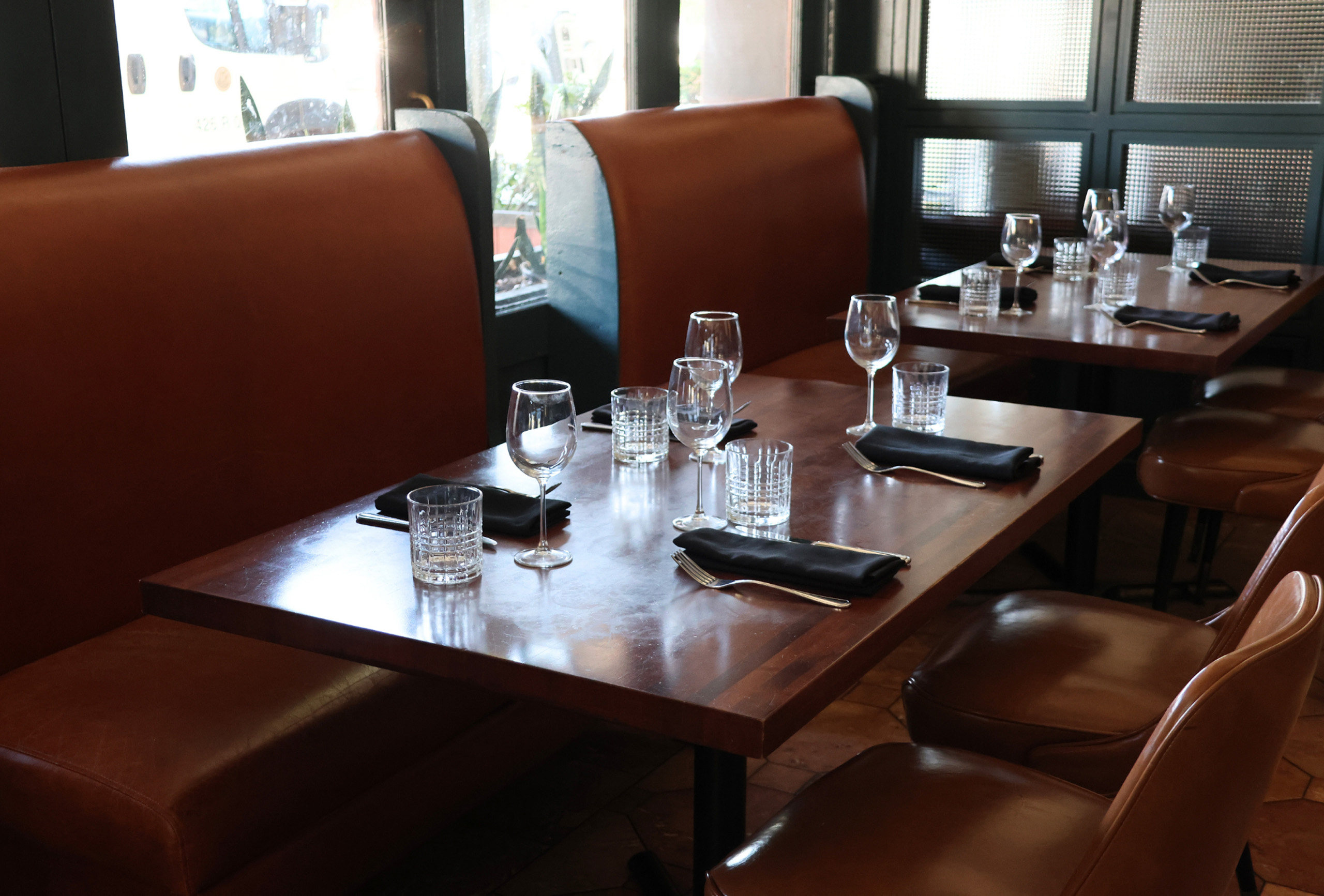 Restaurant booth seating with neatly set tables and glassware.